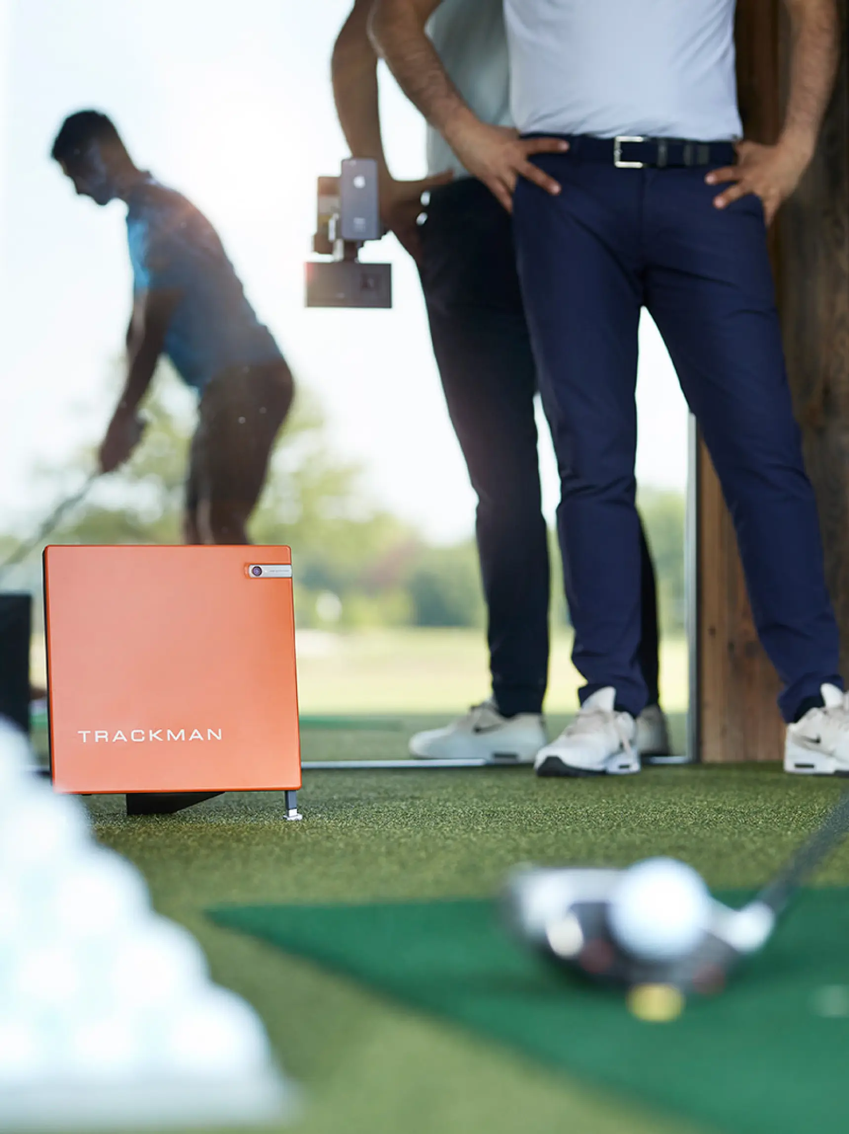 TrackMan golf simulator at Bernardus Golf driving range with golfer in action in the background